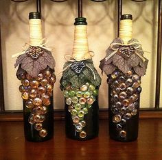 three wine bottles are decorated with grapes