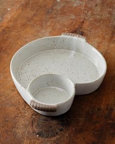 two white dishes sitting on top of a wooden table