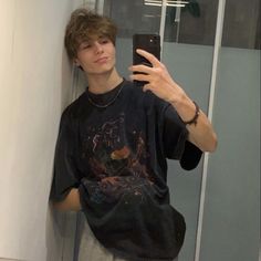 a young man taking a selfie in front of a mirror with his cell phone