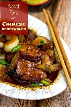 a white plate topped with meat and vegetables next to chopsticks