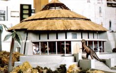 a model of a house with a dinosaur on the front porch and stairs leading up to it