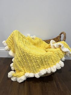 a yellow and white blanket sitting on top of a wooden floor next to a basket