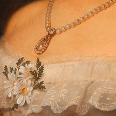 a close up of a woman's white dress with flowers on the chest and necklace