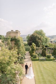 the bride and groom are walking down the path to their wedding ceremony in an english country garden