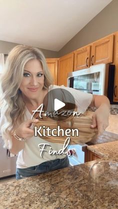 a woman is holding some wood in her hand while standing at the kitchen counter with an american kitchen fund logo on it