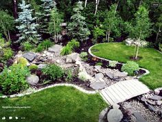 an aerial view of a garden with rocks and grass in the foreground, surrounded by trees