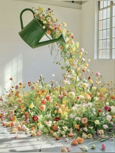 a bunch of flowers that are sitting in the ground with a watering can over them