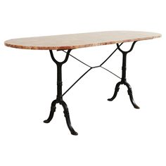 an iron and marble dining table with two legs on each side, the top has a circular