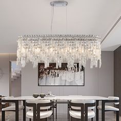 a chandelier hanging from the ceiling in a dining room with white chairs and table