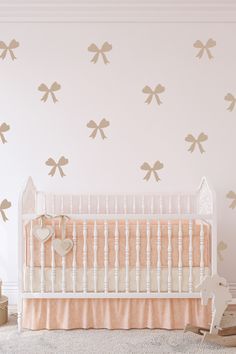 a white crib in front of a wall with gold bow decals on it