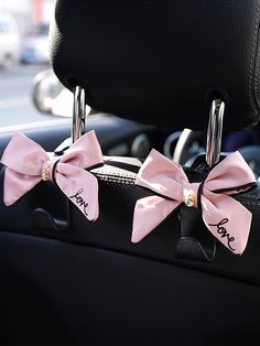 two pink bows are attached to the front seat of a car with initials on them