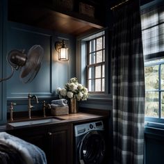 a washer and dryer in a small room with blue walls, wood floors and windows