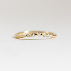 a yellow gold ring with five diamonds on it's side, sitting on a white surface