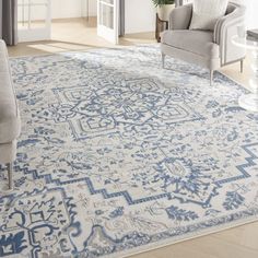 a blue and white area rug with an ornate design on the bottom, in front of a chair