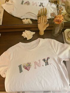 a t - shirt with the word love written on it next to flowers and other items