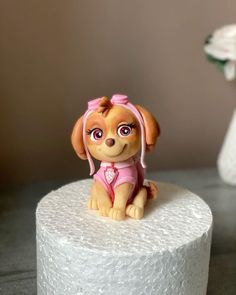 a small dog figurine sitting on top of a white toilet paper roll next to a flower