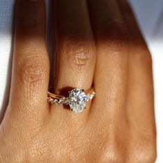 a woman's hand with a diamond ring on top of her finger, showing the center stone