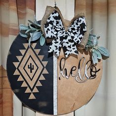 a wooden sign with the word hello written on it and a bow at the top