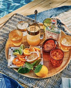 an assortment of drinks on a wicker tray by the pool