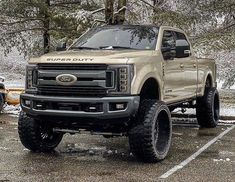 a truck parked in a parking lot with snow on the ground and trees behind it