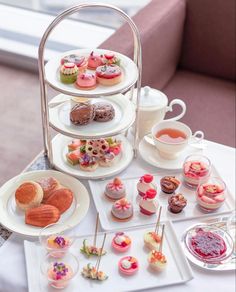 a table topped with plates filled with different types of pastries and desserts next to a window