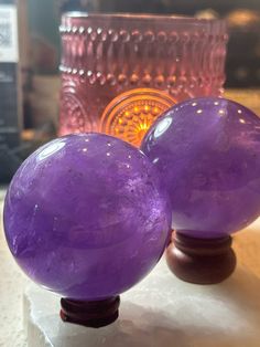 two purple glass balls sitting on top of a table