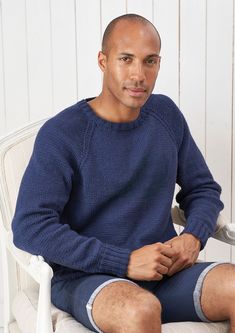 a man sitting in a chair with his legs crossed and looking at the camera while wearing shorts