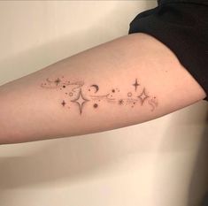 a woman's arm with stars and moon tattoos on it