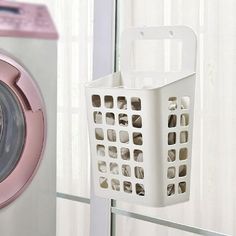 a laundry basket hanging from the side of a dryer door next to a washing machine