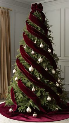 a christmas tree decorated with red velvet ribbons and white baubles in a living room