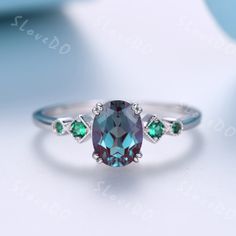 a ring with an oval cut blue topazte surrounded by green emeralds