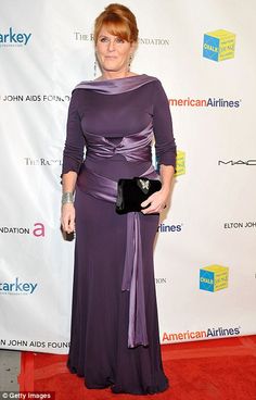 a woman in a long purple dress standing on a red carpet with an american airlines sign behind her