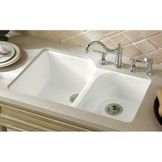 a white sink sitting under a faucet next to a counter top with dishes on it