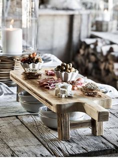 a wooden table topped with plates and bowls filled with different types of food next to a lit candle