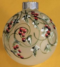 a glass ornament with red berries and leaves painted on the inside of it