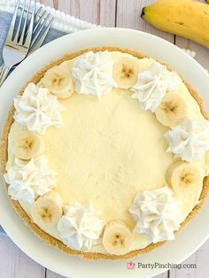 a banana cream pie on a white plate with a fork and knife next to it