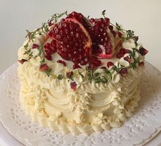 a cake with white frosting and pomegranates on top, sitting on a plate