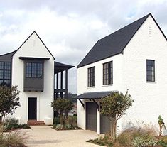 two large white houses with black windows next to each other