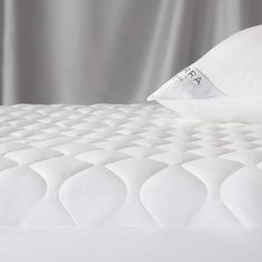 a close up view of a mattress with white sheets and pillows on the bottom half