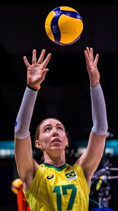 a female volleyball player is reaching up to hit the ball