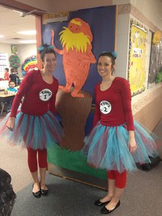 two girls dressed in costumes standing next to each other near a sign that says dr seuss