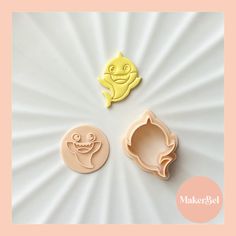 two cookie molds with faces on them sitting next to each other in front of a pink and white background