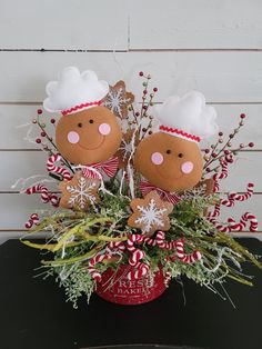 two stuffed gingerbreads in a red pot with candy canes and greenery