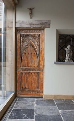 a large wooden door sitting next to a window on top of a stone flooring