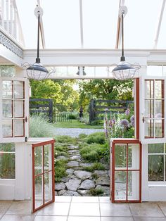 an open door leading into a garden with flowers and rocks in the ground, surrounded by greenery