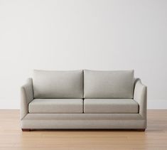 a couch sitting on top of a hard wood floor next to a white painted wall