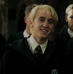 two young men dressed in harry potter school uniforms, one with blonde hair and the other with blue eyes