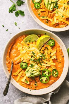 two bowls filled with chili and cheese soup