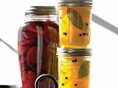 four jars filled with pickles sitting on top of a table next to each other