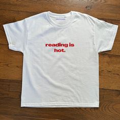 'reading is hot' Baby Tee Reading Is Hot Baby Tee, Heavy Cotton, Iconic Slogan T-shirt, 90s Aesthetic Vintage Tee Trending Print Top  - 90's Baby tee style (made for adults) - 100% cotton - Classic fit - Runs true to size (refer to size chart) - Tear-away label - Y2K Vintage Streetwear Trending Fashion - Environmentally sustainable made-to-order system Baby tee's were popularised in the '90s, characterised by it's very short sleeves and slightly cropped body, creating a very flattering feminine Cute Swear Shirt, Popular T Shirt Design Ideas, Cool Printed Shirts, Iconic T-shirts, Simple Iron On Shirts, Fun Baby Tees, Reading Is Hot Shirt, Cheap Basic Tops With Embroidered Text, Vintage T Shirt Aesthetic